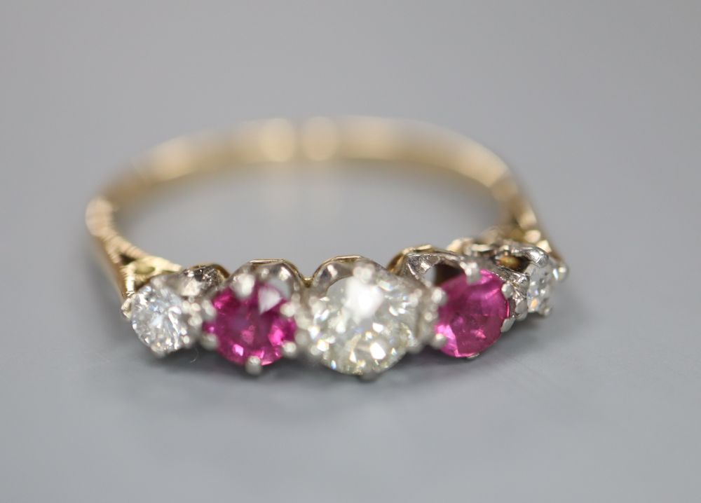 An early 20th century yellow metal and plat, three stone ruby and two stone diamond set half hoop ring, size Q, gross 2 grams.